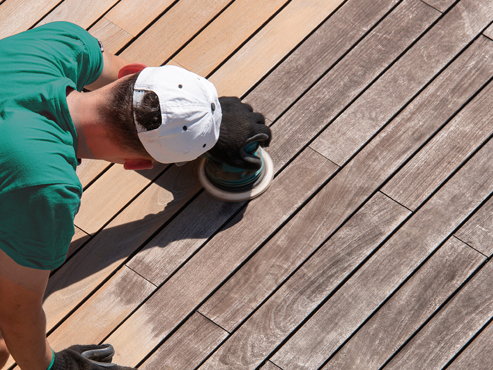 man sanding wood deck